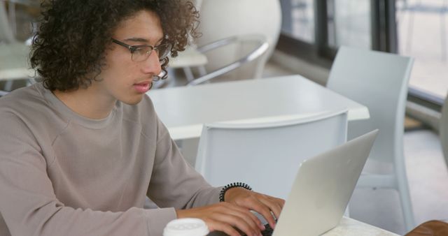 Young Man Working on Laptop in Cafe with Large Windows - Download Free Stock Images Pikwizard.com