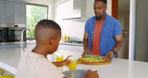 Father and Son Enjoying Pizza at Modern Kitchen Island