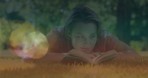Young Woman Relaxing on Lawn While Reading Book