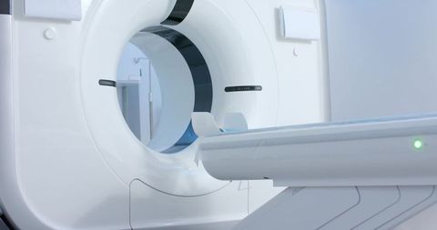 Modern ct scanner gantry with motorized patient table sliding into bore for diagnostic radiology