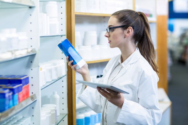 Pharmacist holding digital tablet while checking medicine in pharmacy