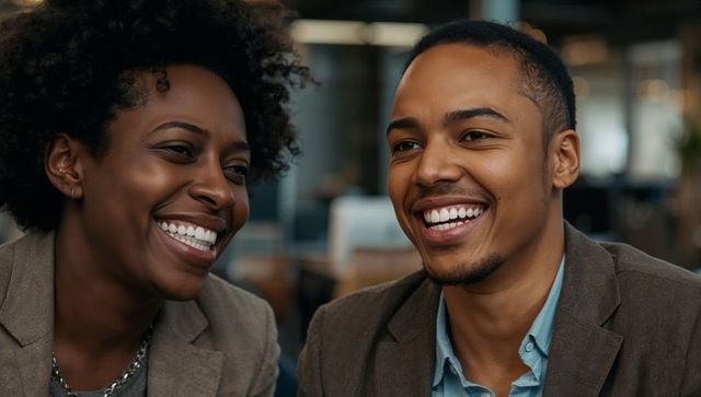 Smiling black professionals collaborating and laughing in modern office, teamwork focus