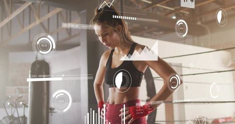Female boxer standing in industrial gym viewing ar fitness metrics wearing red hand wraps