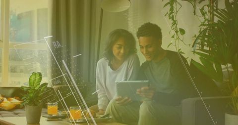 Couple Relaxing at Home Sharing Tablet and Drinks