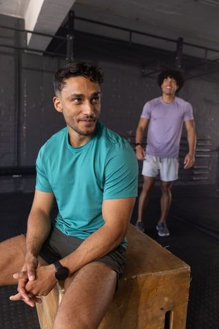 Men resting on plyometric box in fitness gym