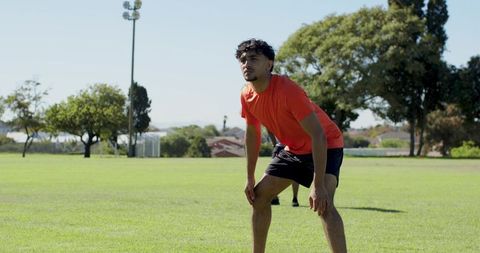 Young athlete catching breath on grass after sprinting during outdoor soccer practice