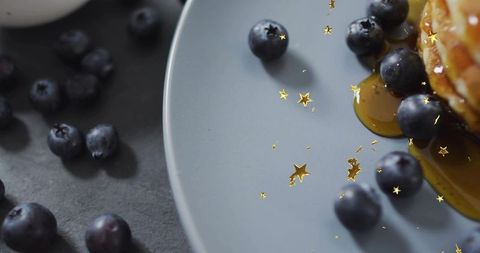 Gourmet blueberry pancake stack dripping maple syrup with gold star sprinkles macro closeup
