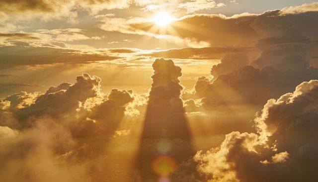 Golden Dramatic Crepuscular Rays Casting Towering Cumulus Shadow Across Sunlit Cloudscape