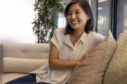 Asian woman smiling on sofa in modern office lounge