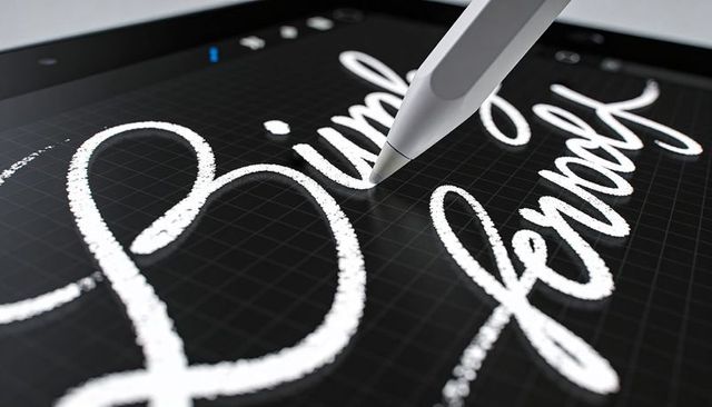 Stylus creating chalk textured calligraphy on tablet screen with grid interface closeup