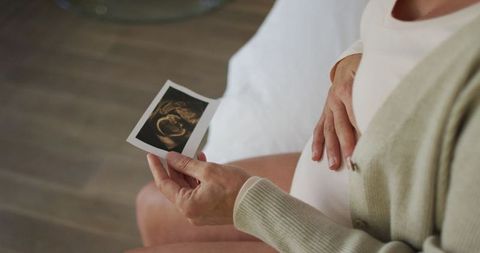 Pregnant woman holding ultrasound over belly