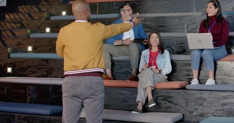 Young african american presenter engaging diverse team on tiered steps during workshop