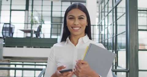 Confident Businesswoman Holding Notebook and Phone in Office - Download Free Stock Images Pikwizard.com