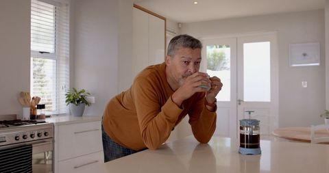 Senior Man Enjoying Morning Coffee At Home in Cozy Kitchen
