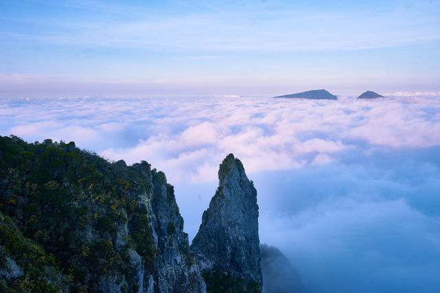 Picture showcasing rugged mountain peaks piercing through an expanse of clouds during sunrise. Ideal for use in nature documentaries, travel blogs, outdoor adventure advertisements, scenic calendars, or inspirational posters highlighting natural beauty and majesty.