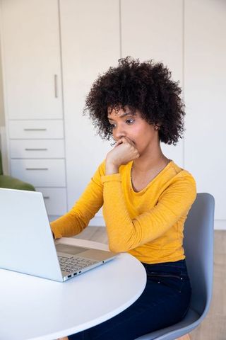 African American Woman Focused on Laptop in Bright Home Office