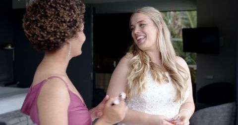 Joyful Bride and Bridesmaid Preparing for Wedding in Bedroom