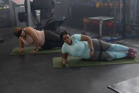 Diverse women holding side planks on mats in gym practicing core strength and balance