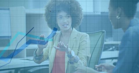 Discussing data trends: curly-haired woman gesturing to growth charts in open office