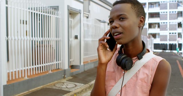 Teenager Talking on Smartphone Outdoors with Headphones Around Neck - Download Free Stock Images Pikwizard.com