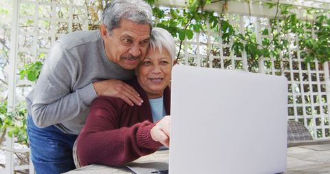 Senior Biracial Couple Using Laptop in Garden
