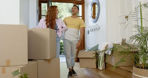 Excited Couple Unpacking in New Home Surrounded by Cardboard Boxes