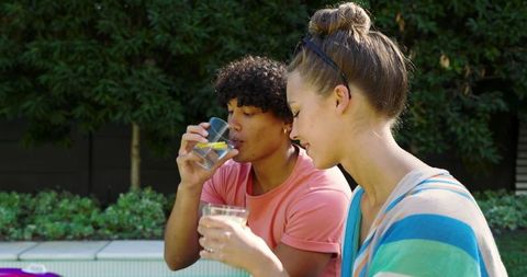 Friends Relaxing by Backyard Pool with Lemon Water in Summer