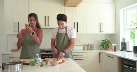 African american couple cooking together in bright modern kitchen chopping and seasoning