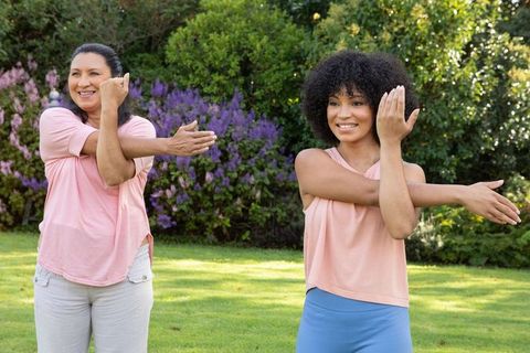 Mother and Daughter Stretching Arms in Sunny Backyard