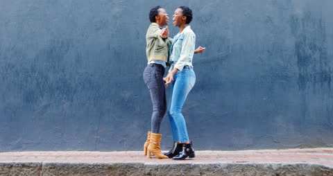 Joyful Twin Sisters Embracing on Urban Sidewalk