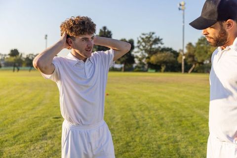 Young player receiving coaching feedback from diverse coach on sunlit sports field