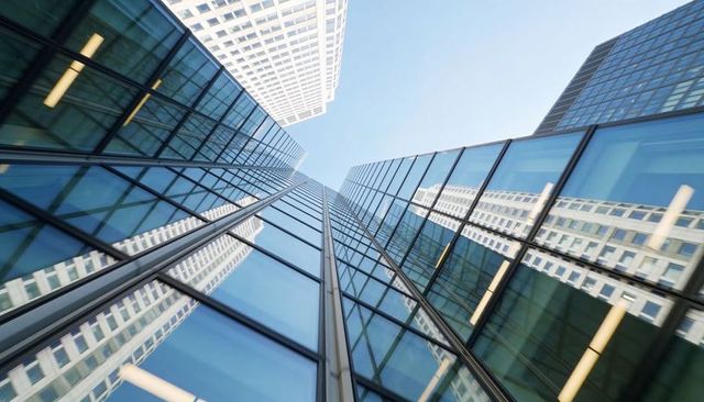 Glass skyscraper converging toward sky, reflecting white grid tower, urban perspective