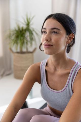 Calm young woman practicing mindfulness and stretching on yoga mat in bright home interior