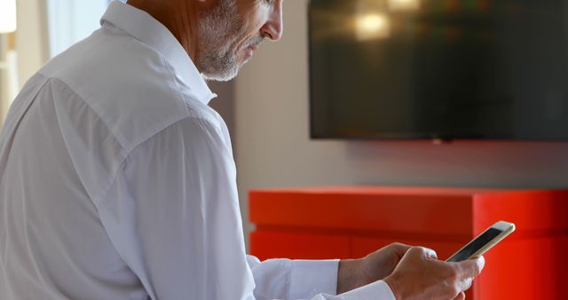 Middle-aged man using smartphone in modern living room - Download Free Stock Images Pikwizard.com