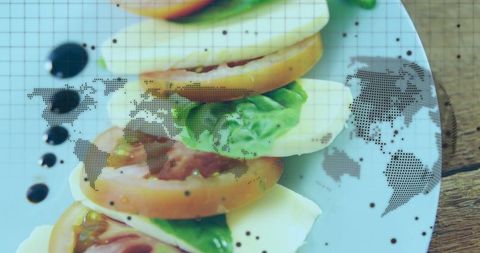 Caprese salad layering with balsamic glaze and dotted world map overlay