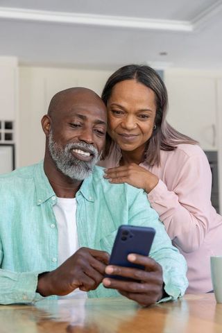 Senior couple sharing joyful moment using smartphone in cozy kitchen