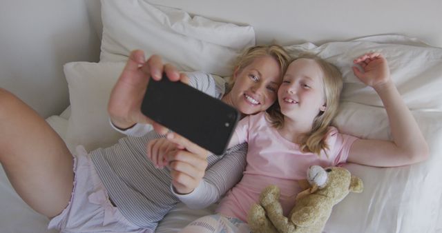 Mother and Daughter Bonding While Taking a Selfie in Bed - Download Free Stock Images Pikwizard.com