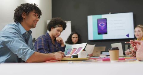 Diverse creative team reviewing mobile app mockups and ui color concepts during brainstorming