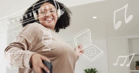 Joyful woman dancing at home with wireless headphones and smartphone, music doodles