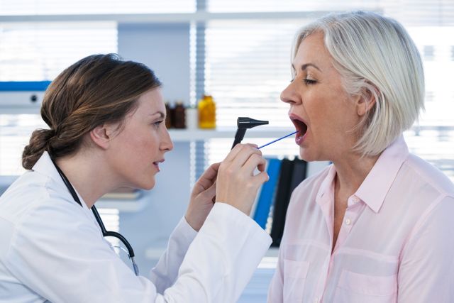Doctor examining patient's mouth with an otoscope in a modern clinic. Ideal for illustrating medical checkups, doctor-patient interactions, healthcare services, and professional consultations. Great for use in healthcare websites, medical brochures, and educational materials.