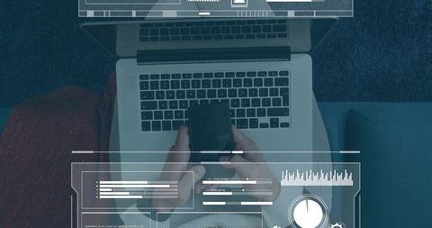 Man working from sofa holding smartphone over laptop with hud analytics overlay for remote work