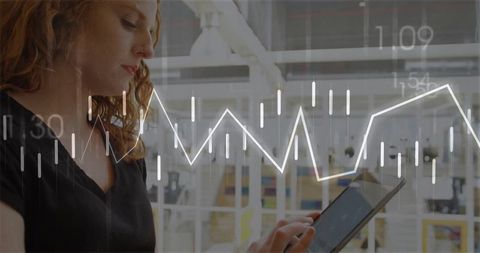 Red-haired woman analyzing financial graph on tablet in modern office