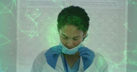 Nurse adjusting surgical mask wearing gloves and scrubs with green digital network overlay