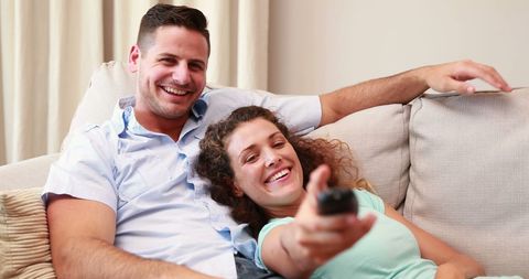Happy Couple Enjoying Time Watching Television Together on Sofa