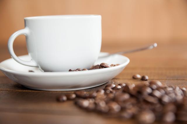 Cup of coffee with coffee beans and spoon on wooden table