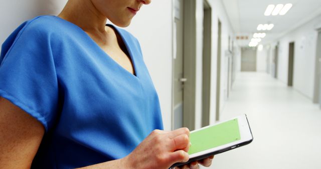 Doctor using a tablet in a hospital hallway, focusing on modern healthcare and technology. Ideal for articles and advertisements about advancements in medicine, electronic health records, and the integration of technology in hospitals. Can be used in medical journals, healthcare websites, and technology magazines.