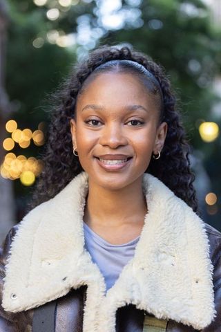 Smiling african american woman wearing shearling coat and gold hoops in evening park