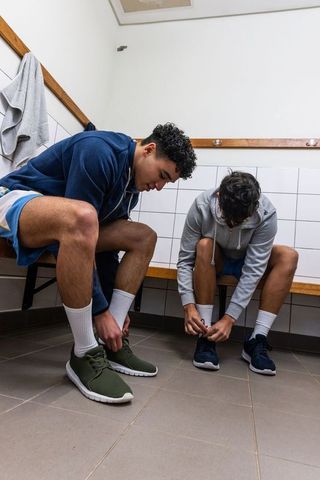 Teenage Male Teammates Tying Shoelaces in Locker Room