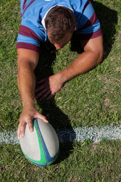 High angle view of a rugby player holding a ball on the goal line, ideal for sports-related content, articles on rugby techniques, teamwork, and athletic achievements.