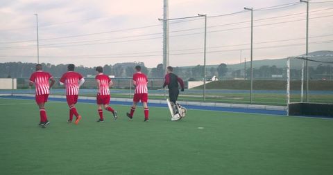 Field Hockey Athletes Running Toward Goal on Artificial Turf
